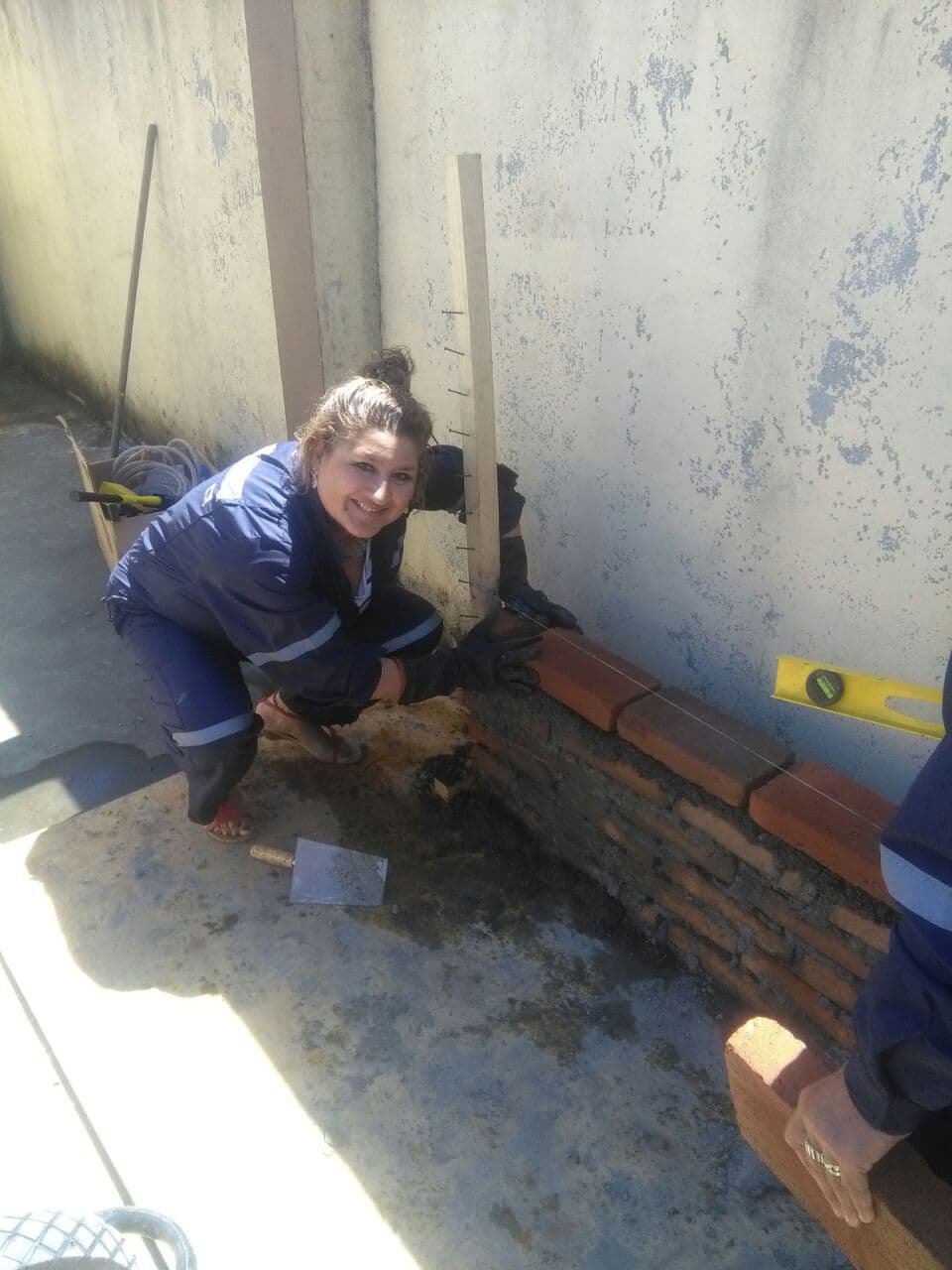 Participante aprendiendo albañilería, levantando un muro de ladrillo