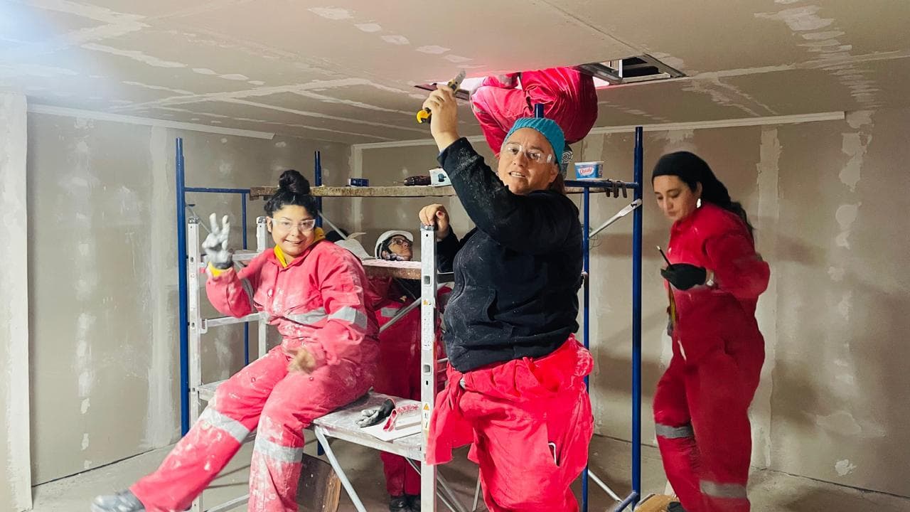 Participantes con overol instalando un cielo de volcanita